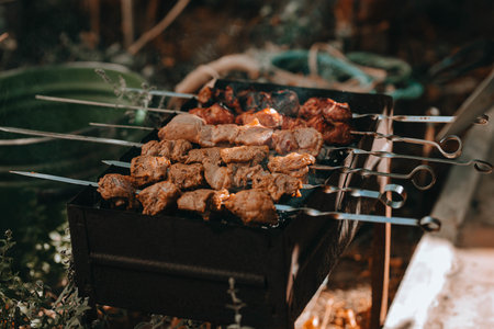 traditional kebab. Juicy roasted hot meat on iron skewers. Barbecue. Fresh, home-made on grill fire meat pork shashlik kebab on a sunny day close up outdoors at back yard. picnic. Tasty BBQ foodの写真素材
