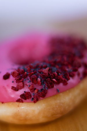 The Fully Close-up Of The Donut With Pink Icing And Colored Sprinkles with poppy seeds. sideview....