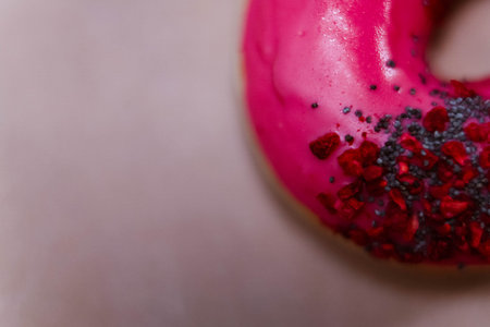 The Fully Close-up Of The Donut With Pink Icing And Colored Sprinkles with poppy seeds. top view....