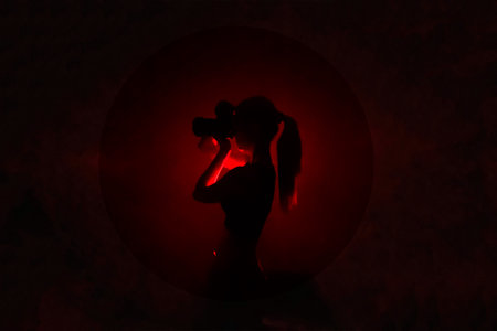 Center red light silhouette on black background and lady photographer with camera taking photos. concept of art photography. Dark picture for website, avatar, Surreal Black and red abstract backdropの写真素材