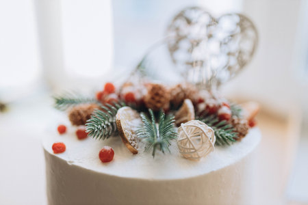 white holiday white cake covered with chocolate coins, snowball and spruce tree branches, pinecones and wooden heart. On the cake, the number 2021 is put out in red berries. The concept of a new year.の写真素材