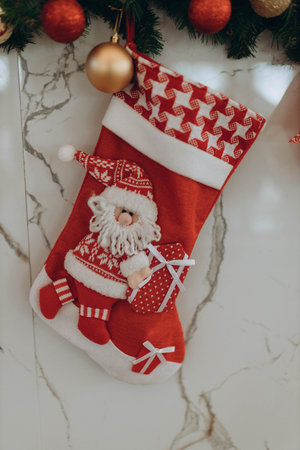 red Christmas stockings on fireplace decorated with Handmade Santa Claus. Minimal New Year season concept. Top view, flat lay on marble background. Composition sock hanging on white wallの写真素材