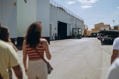 Villajoyosa, Spain - May 16, 2023: Two woman from the tourists group at the factory "Valor" going during excursion outside the yard.のeditorial素材