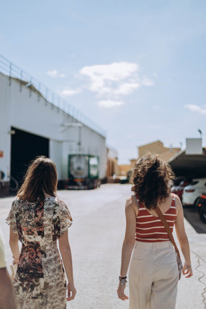 Villajoyosa, Spain - May 16, 2023: Two woman from the tourists group at the factory "Valor" going during excursion outside the yard.のeditorial素材