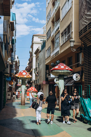 Alicante, Spain - May 16, 2023: People walking funny street Calle de Las Setas (The Mushroom Street) in Alicante old town. Fly agaric (or amanita muscaria) mushrooms creative street design.のeditorial素材