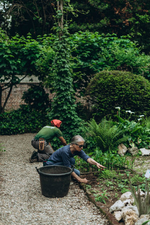 Milan, Italy- May 13, 2023: Caring for plants. Old people gardener sitting working in botanical garden, part of the Brera Academy complex, Milan city center, Italyのeditorial素材