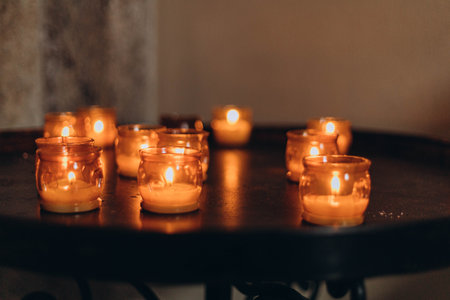 Picture of Easter candles burning at night with golden light of candle flame. Lampion candles glowing in a dark church. emotional mood. Many burning candles with shallow depth of fieldの写真素材