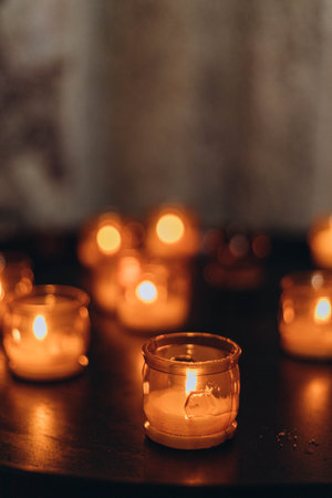 Picture of Easter candles burning at night with golden light of candle flame. Lampion candles glowing in a dark church. emotional mood. Many burning candles with shallow depth of fieldの写真素材