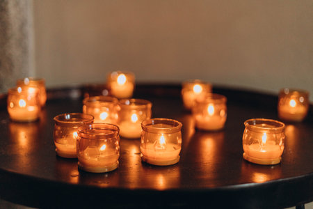 Picture of Easter candles burning at night with golden light of candle flame. Lampion candles glowing in a dark church. emotional mood. Many burning candles with shallow depth of fieldの写真素材