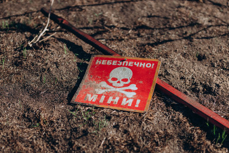 Mykolaiv region, Ukraine - 10 October 2023. Translation: "Dangerous, mines!" danger minefield in Former Russian army position. White skull-and-crossbones symbol on a red sign warning of the dangerのeditorial素材