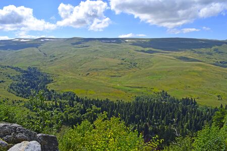 Beautiful hills, meadows and green pines. Blue sky and white clouds. Summer landscape, sunny day. Horizontal photography. Plateau Lago-Naki, Adygea.の写真素材