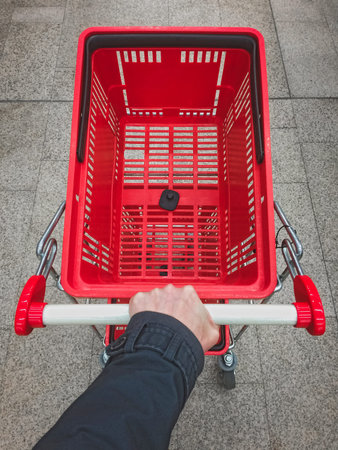 Male hand pushing empty shopping cart. Personal point of view.の写真素材