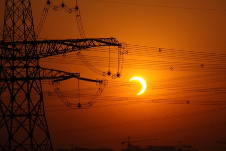 Partial eclipse on high-voltage in the eveningの写真素材