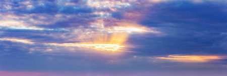 background, panorama of the sky, the suns rays make their way through the dark dramatic cloudsの写真素材