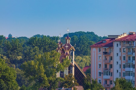 Modern buildings and church among the park trees, blue skyの写真素材