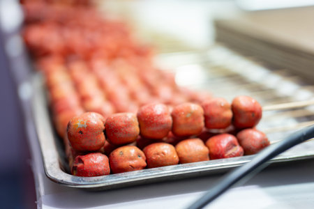 Grilled meatballs on metal tray at food stall, warm lighting and shallow depth of fieldの写真素材