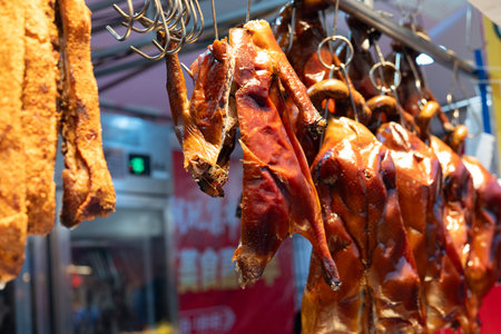 Roasted ducks hanging on hooks at street food market with glossy skin and warm lightingの写真素材