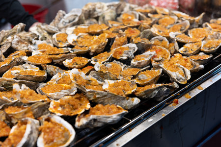 Grilled oysters with garlic topping on metal grill at food stallの写真素材