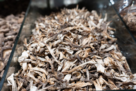 Dried mushrooms piled in glass container, rustic kitchen display with earthy tones and natural textureの写真素材