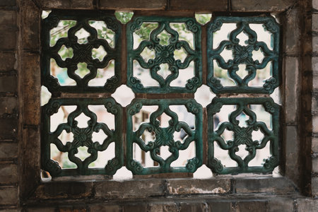 Ornate Green Metal Window Grille with Geometric Patterns Set in Stone Wallの写真素材