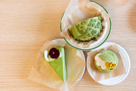 Green Matcha Desserts on Wooden Table with Paper Wraps and Edible Flowersの写真素材