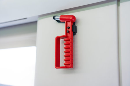 Red car safety hammer mounted on white interior panel, emergency tool for vehicle escapeの写真素材