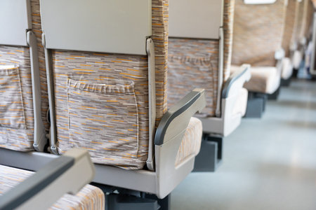 Row of modern train seats with patterned fabric upholstery in passenger compartment