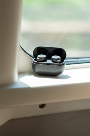 Wireless earbuds in open charging case resting on windowsill with natural light