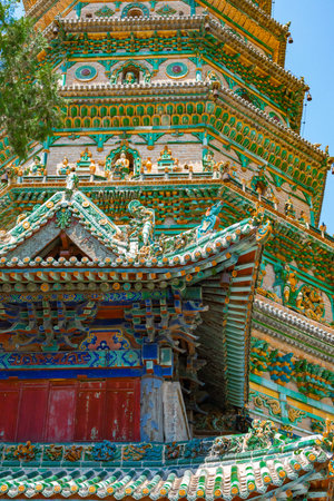 Colorful Traditional Chinese Pagoda with Intricate Roof Tiles and Ceramic Decorations Under Blue Sky