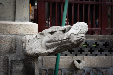 Stone dragon head sculpture on ancient building wall, weathered texture, traditional Chinese architecture detailの写真素材