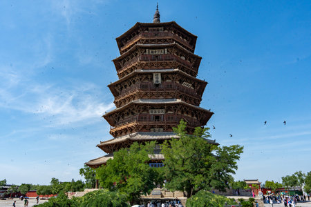 Ancient Wooden Pagoda with Multiple Eaves Under Blue Sky, Tourists Nearbyの写真素材