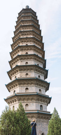 Ancient Chinese Pagoda with Tiered Roofs Against Blue Sky, Tourist Taking Photo at Baseの写真素材