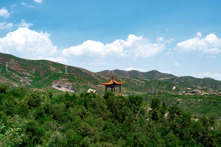 Traditional Chinese Pavilion on Hilltop Amid Green Forests Under Blue Sky with Clouds