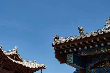 Traditional Chinese temple roof with ornate tiles and decorative statues under clear blue sky