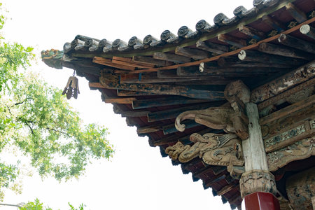 Traditional Chinese Temple Eave with Carved Woodwork and Ceramic Tiles Under Green Trees