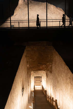 Silhouettes of Visitors Walking Above Ancient Stone Tunnel in Museum Displayの写真素材