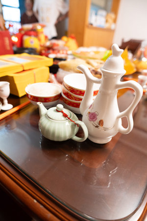 Chinese Tea Set on Polished Wooden Table with Red Bowls and Gift Boxes in Background