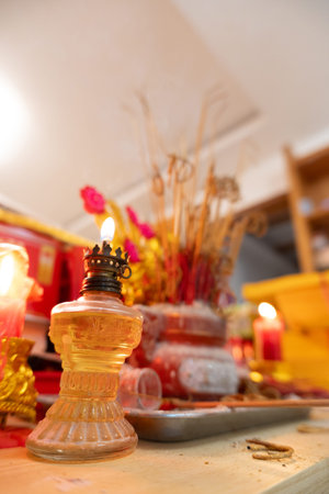 Traditional Asian Temple Altar with Burning Incense, Oil Lamp, and Candles in Warm Indoor Lighting