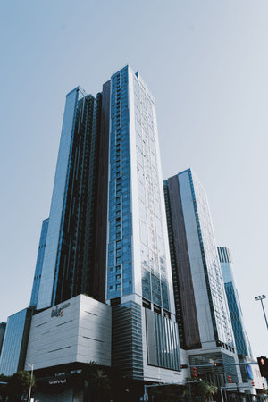 Modern glass skyscrapers in urban cityscape under clear blue sky, reflecting sunlight with sleek...