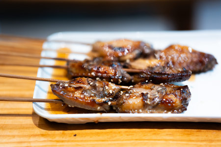 Japanese Yakitori Skewers with Glazed Chicken on White Plate Over Wooden Table