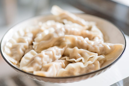Chinese Dumplings in Bowl, Steamed, Fresh, Traditional Cuisine, Served on Table, Soft Texture, Clear Glass Bowl, Warm Lighting, Home Kitchen Settingの写真素材
