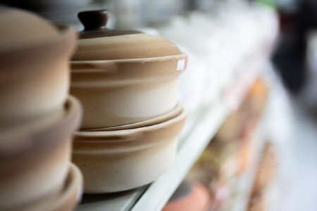 Ceramic pots stacked on shelf in kitchenware store with soft focus background