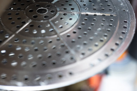Stainless steel steamer basket with perforated holes, close-up view, kitchen cooking tool, metallic...