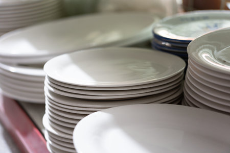 Stacks of white ceramic plates arranged on table surface with soft lighting and blurred background