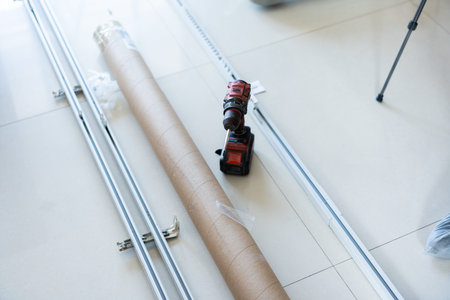 Installation of metal sliding tracks with drill and cardboard tube on tiled floor in modern homeの写真素材