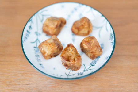 Crispy fried pork belly bites on a floral plate, served in a Japanese-style kitchen setting
