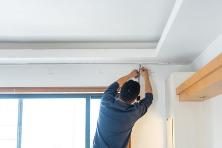 Man installing electrical conduit on ceiling in modern apartment, urban home renovation scene inの写真素材