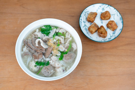Cantonese-style pork and offal soup with fried dumplings served on wooden table in Hong Kongの写真素材