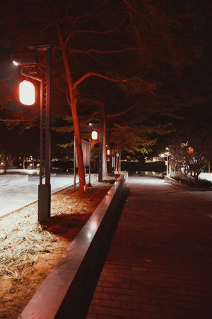 Nighttime urban pathway lined with red-lit lanterns and bare trees in Seoul, South Korea
