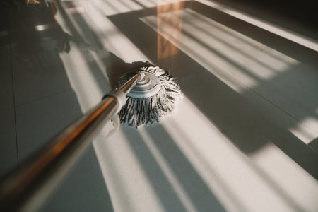 Mop cleaning tiled floor with sunlight shadows in modern home interior